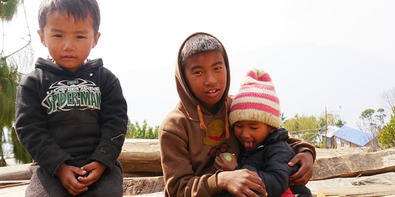 Kinder aus Nepal sitzen auf Holzbrettern