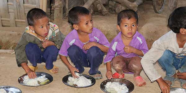 Kinder sitzen auf dem Boden uns essen Reis