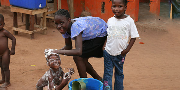 Junges Mädchen wäscht Kleinkind auf dr Straße