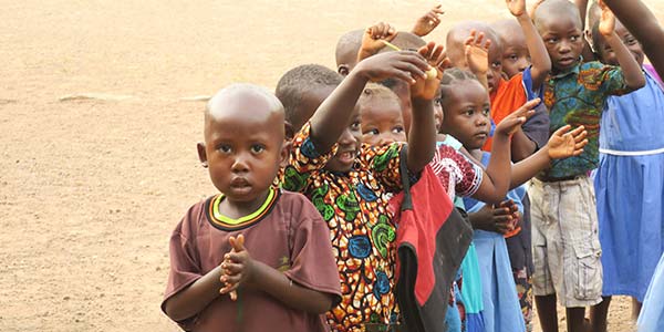 Ebola Waisenkinder stehen in der Reihe hintereinander und winken und klatschen